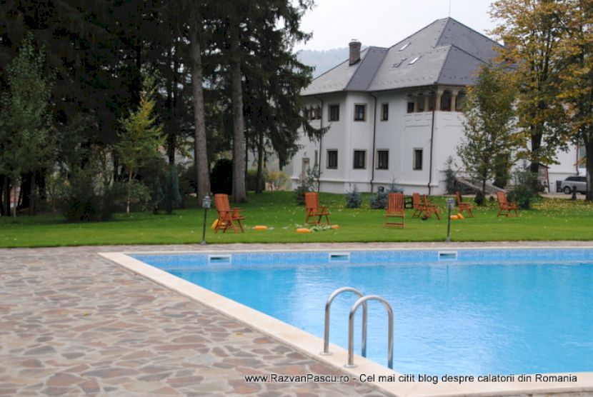 Piscină și clădire albă într-o grădină cu arbori