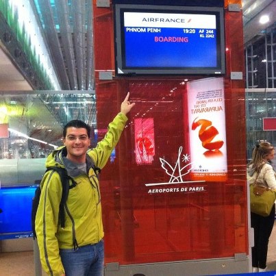 Bărbat cu rucsac arătând spre un ecran de îmbarcare Air France.