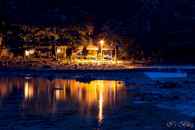 Lumini reflectate în apă lângă o plajă nocturnă