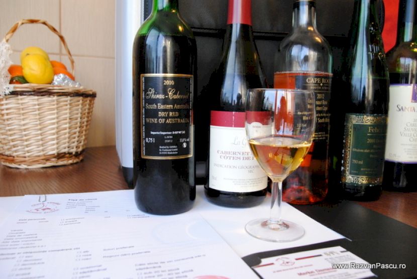 Sticle de vin și un pahar cu vin alb pe masă.