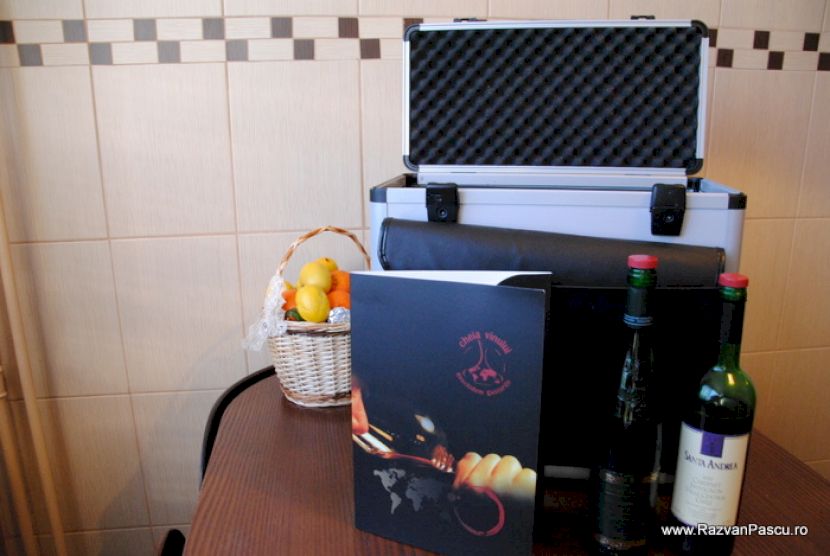 Sticle de vin lângă o valiză deschisă și un coș cu citrice