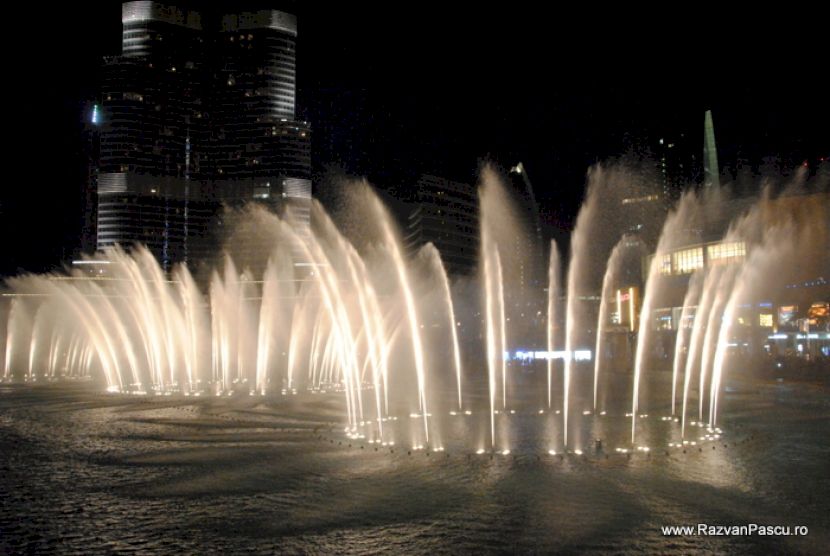 Fântâni cu jeturi luminate pe un lac nocturn