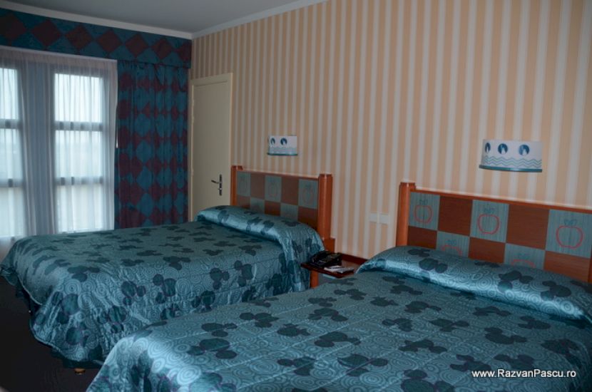 Dormitor cu două paturi albastre și mobilier colorat