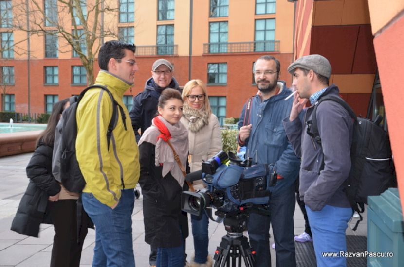 Grup de vizitatori discutând în fața unor clădiri