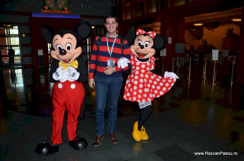 Bărbat între personaje costumate ca Mickey și Minnie Mouse