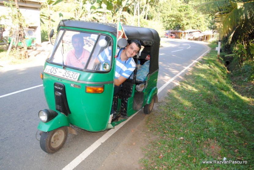 Persoană într-un tuk-tuk verde oprit pe marginea drumului