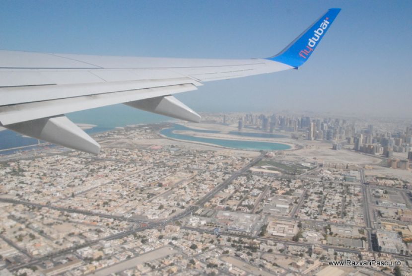 Aripă de avion deasupra unui peisaj urban dens