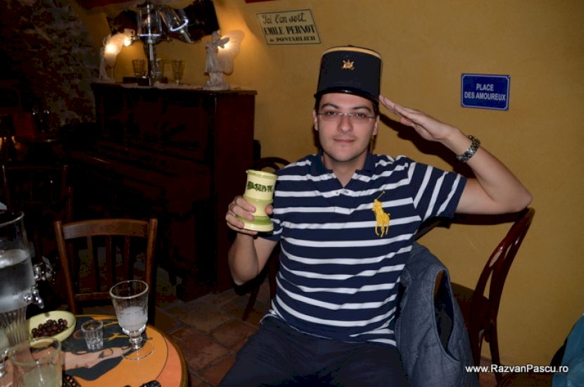 Bărbat cu pălărie într-un bar cu sticle