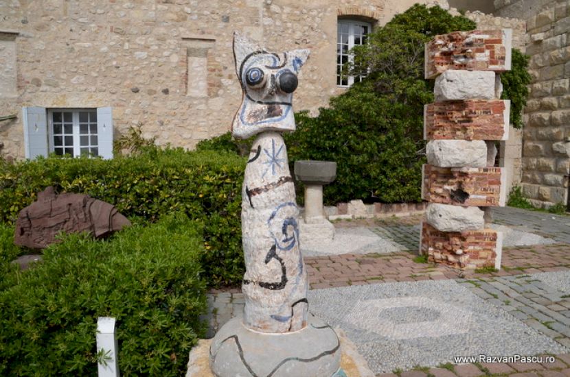 Sculptură în aer liber lângă zid și vegetație