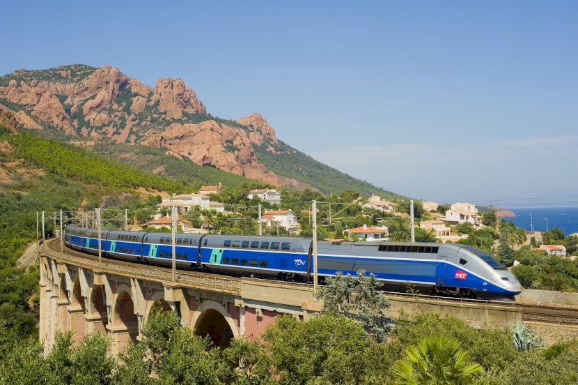 Tren albastru traversând un peisaj de coastă stâncos