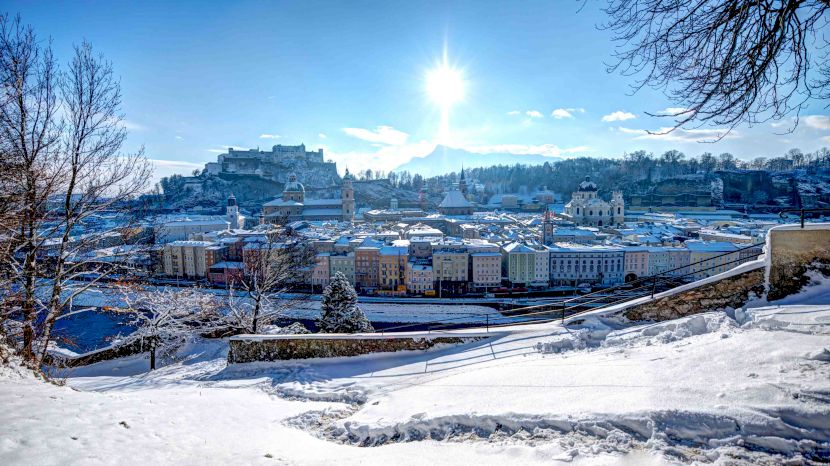 Panoramă de iarnă cu clădiri, pod și cetate pe deal