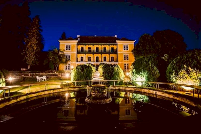 Conac iluminat noaptea, reflectat în apă