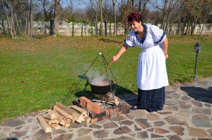 Femeie amestecând într-un ceaun pe foc în aer liber