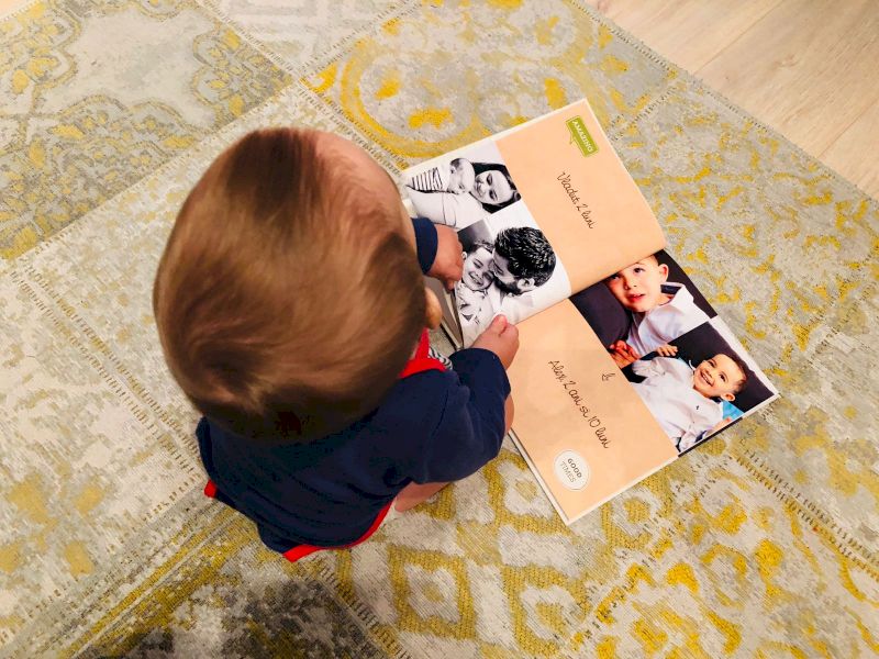 Copil răsfoind un album foto pe covor