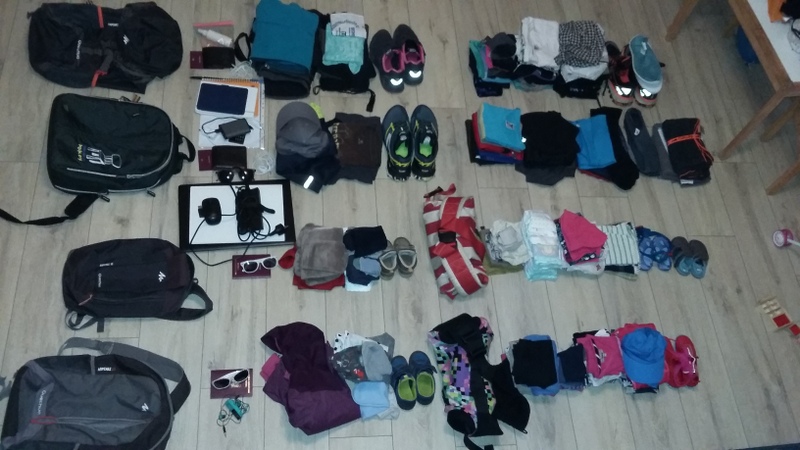 Bagaje, haine și accesorii aranjate pe podea