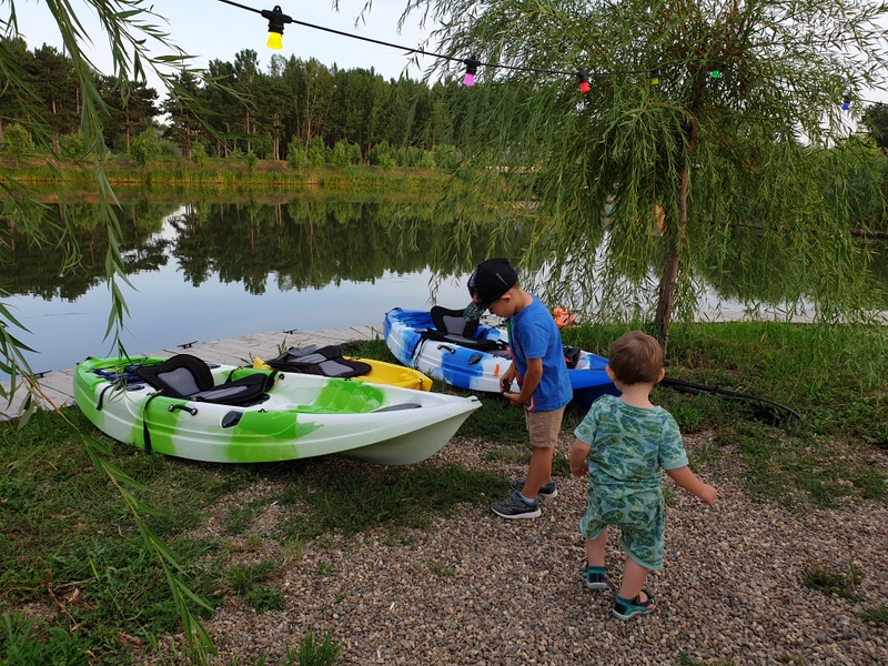 Copii lângă un caiac verde pe mal