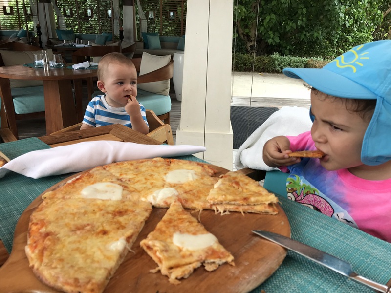 Copii lângă o masă cu pizza și boluri