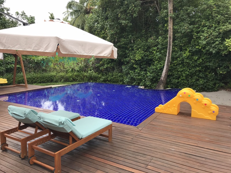 Piscină albastră cu umbrele și tobogan galben