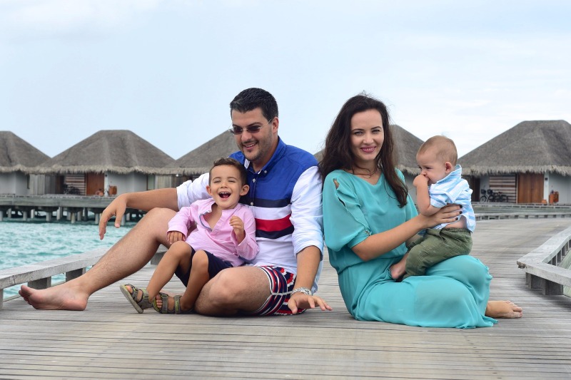 Familie așezată pe ponton, lângă apă turcoaz