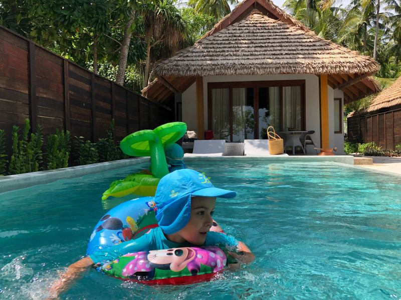 Copil în colac multicolor într-o piscină