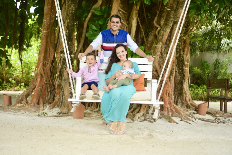 Familie așezată pe un leagăn sub arbori