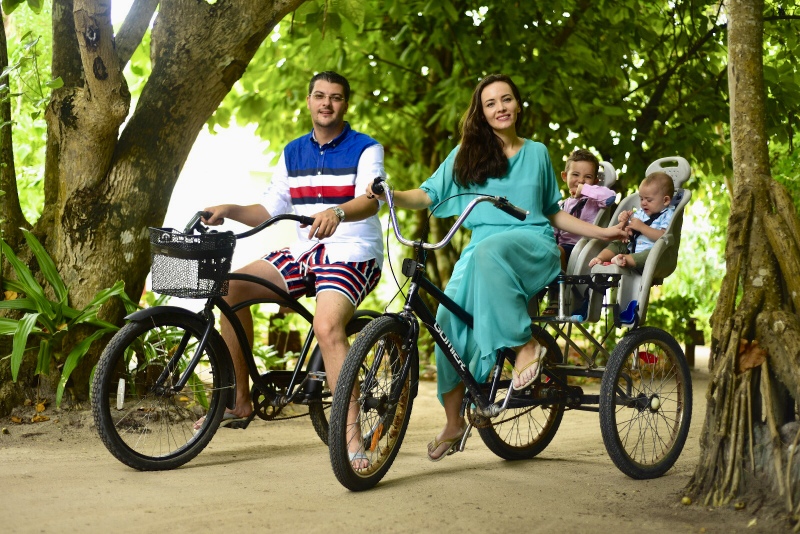 Familie cu biciclete într-o grădină tropicală