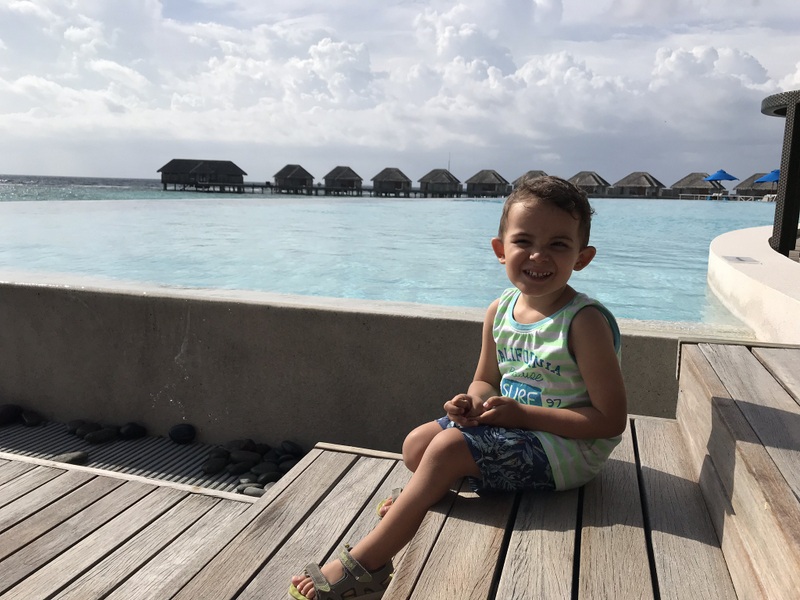 Copil așezat pe un șezlong lângă piscină