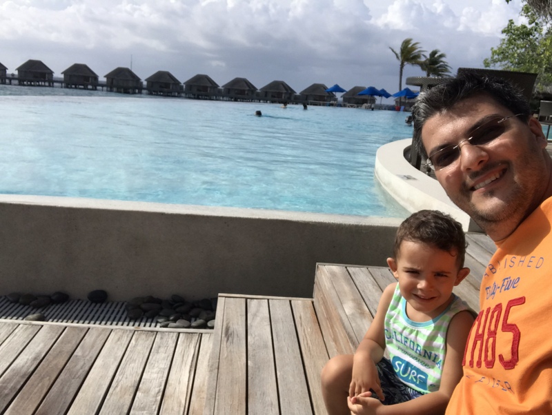 Bărbat și copil lângă o piscină cu vedere spre mare