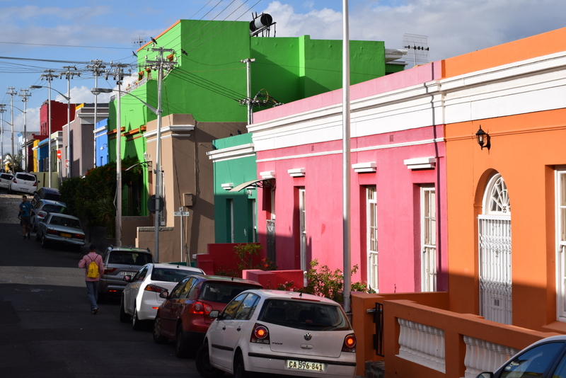 Stradă cu case viu colorate și mașini parcate
