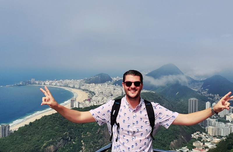 Bărbat cu brațele întinse deasupra panoramei din Rio