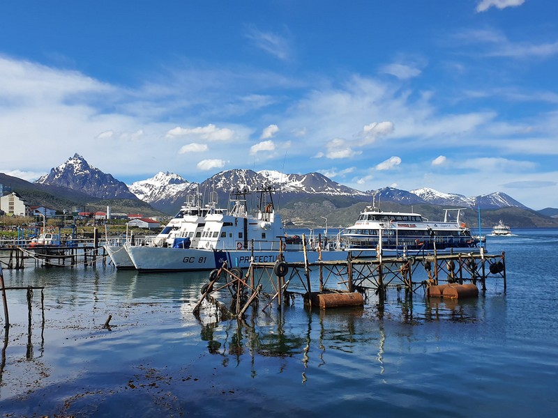 Ambarcațiuni într-un port cu munți în fundal