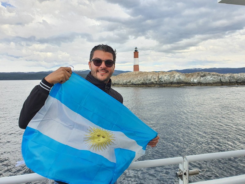 Bărbat ținând steagul Argentinei lângă apă
