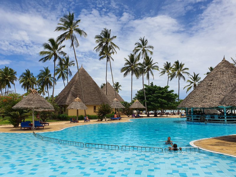 Piscină mare între palmieri și căsuțe