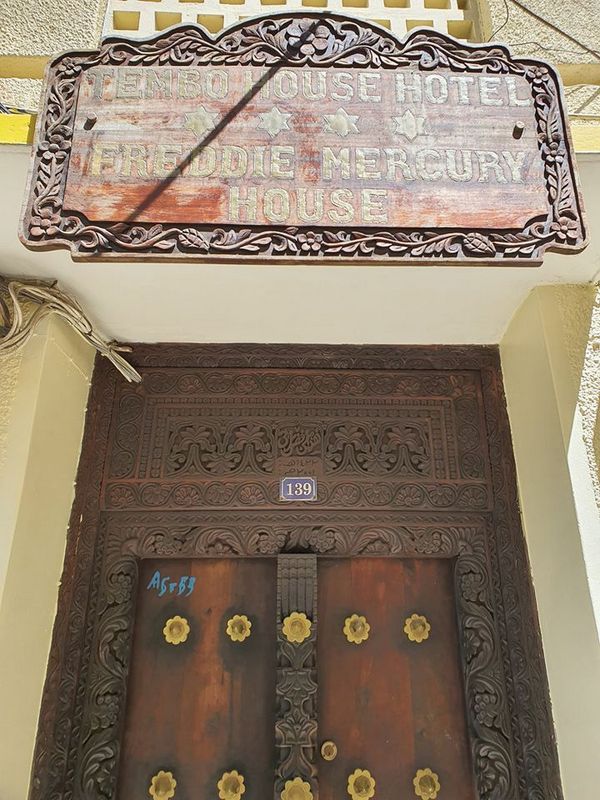 Ușă ornamentată sub un balcon și placă murală