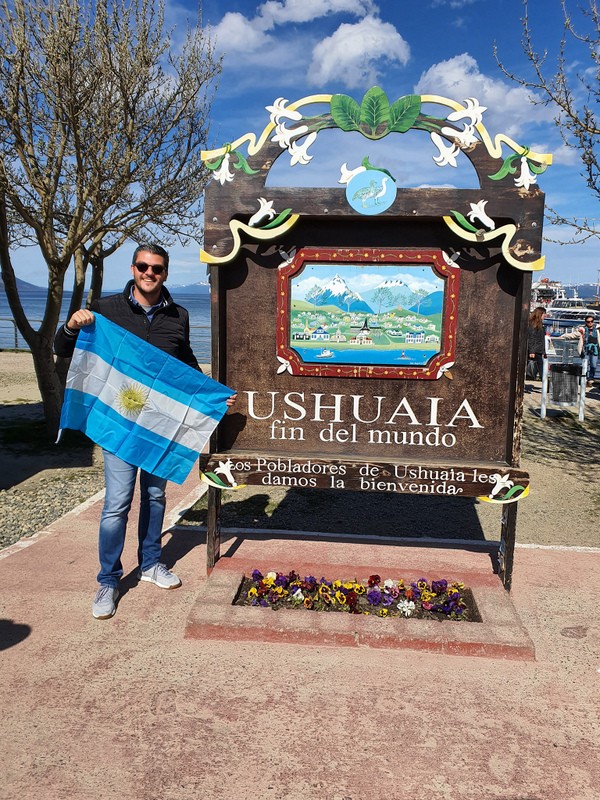 Persoană cu steagul Argentinei lângă un panou decorativ din Ushuaia.