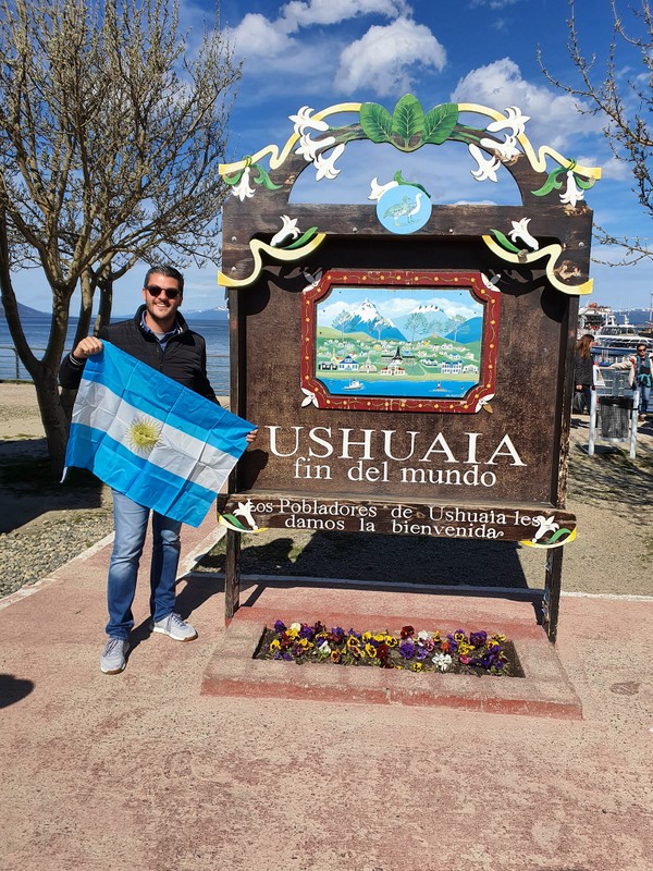 Persoană lângă indicatorul Ushuaia, printre arbori