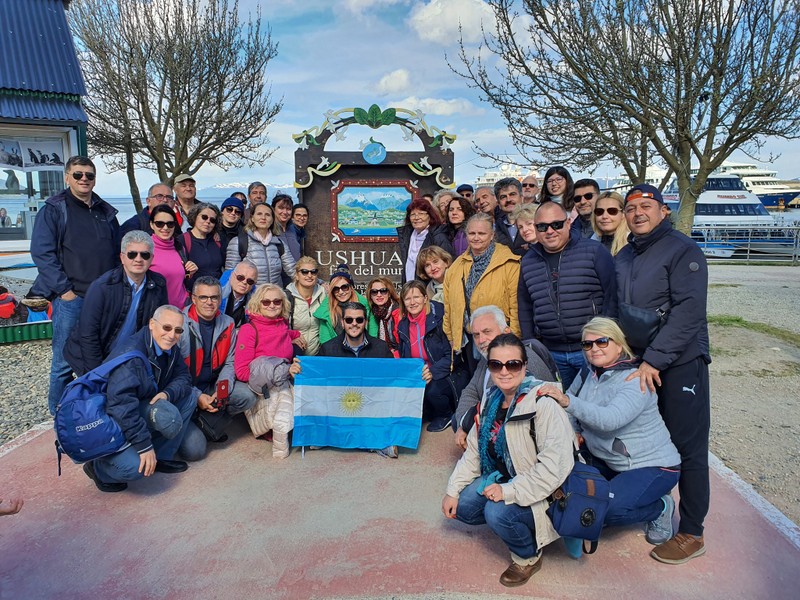 Grup de călători lângă indicatorul orașului Ushuaia