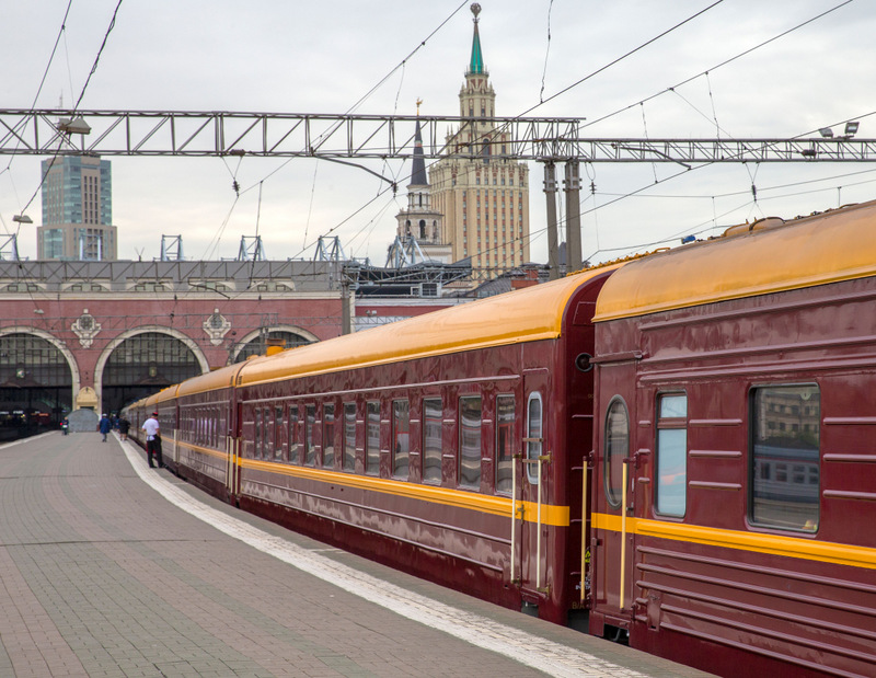 Tren roșu lângă o gară cu turn