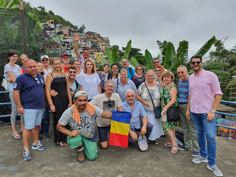 Grup de vizitatori pe o terasă, cu oraș în fundal