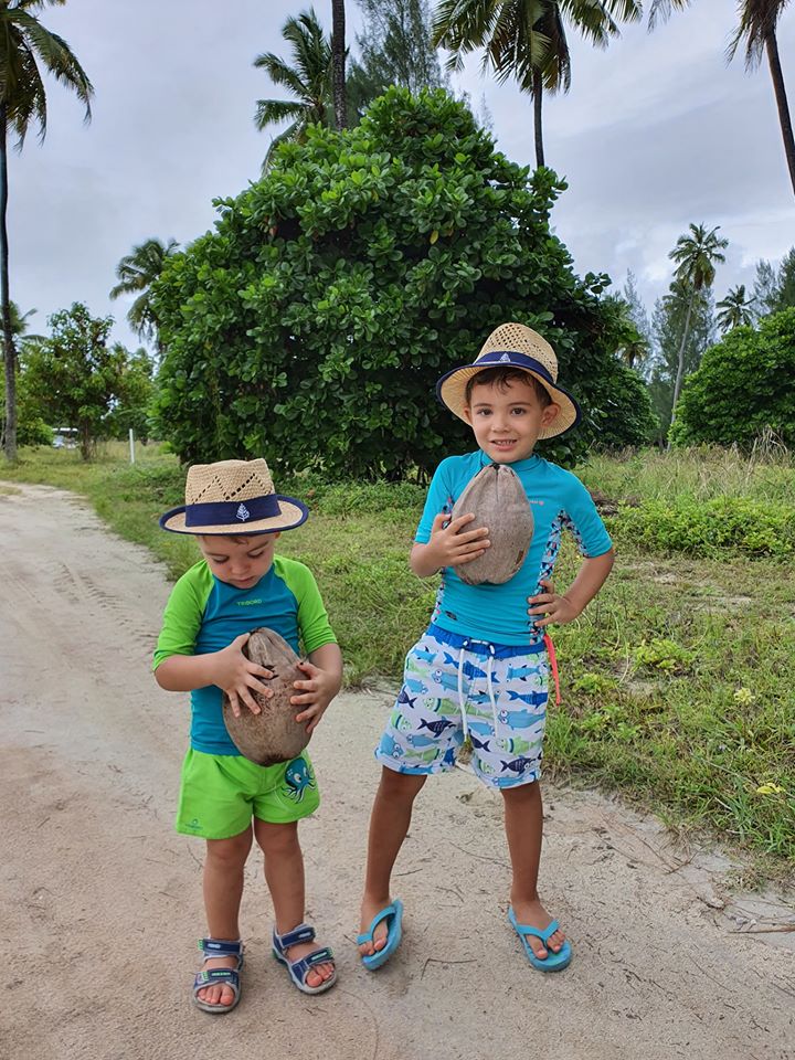 Doi copii cu pălării într-o grădină tropicală