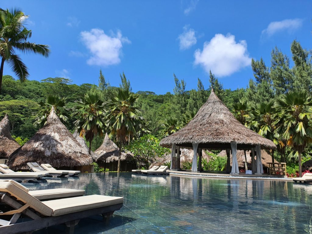 Șezlonguri lângă o piscină cu pavilioane tropicale