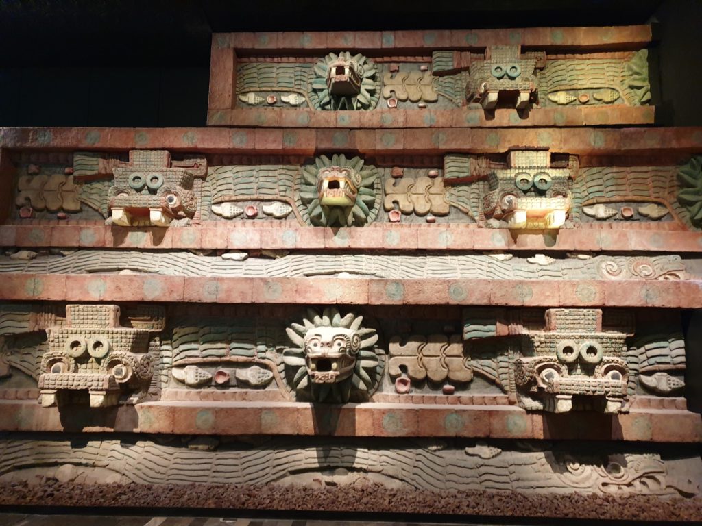 Friză în trepte cu măști sculptate și detalii decorative.