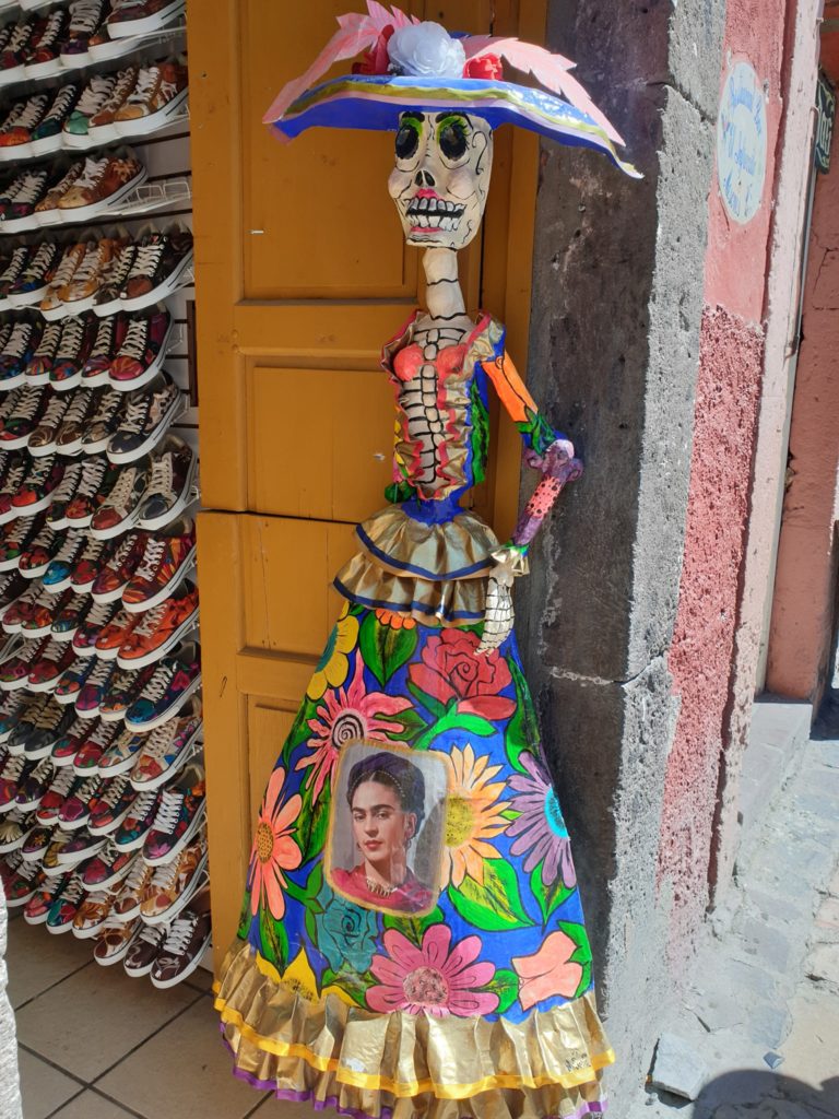Figurină schelet cu rochie florală și pălărie decorată.