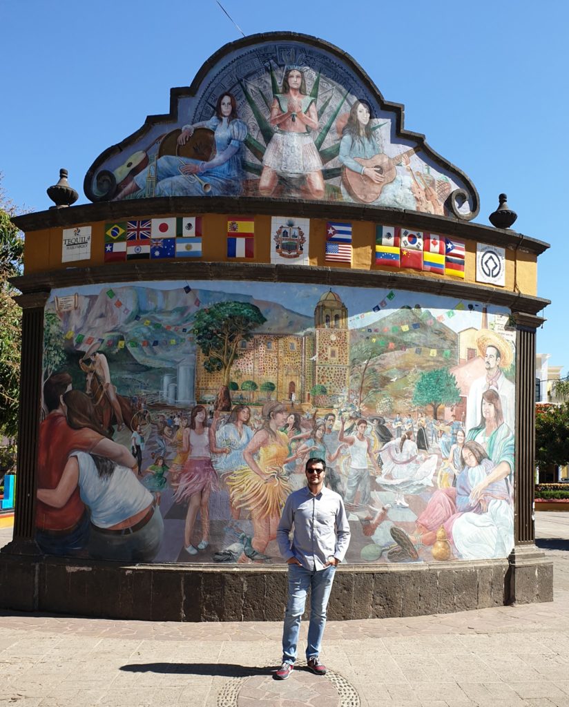 Persoană în fața unei construcții cu picturi murale și fronton decorat.