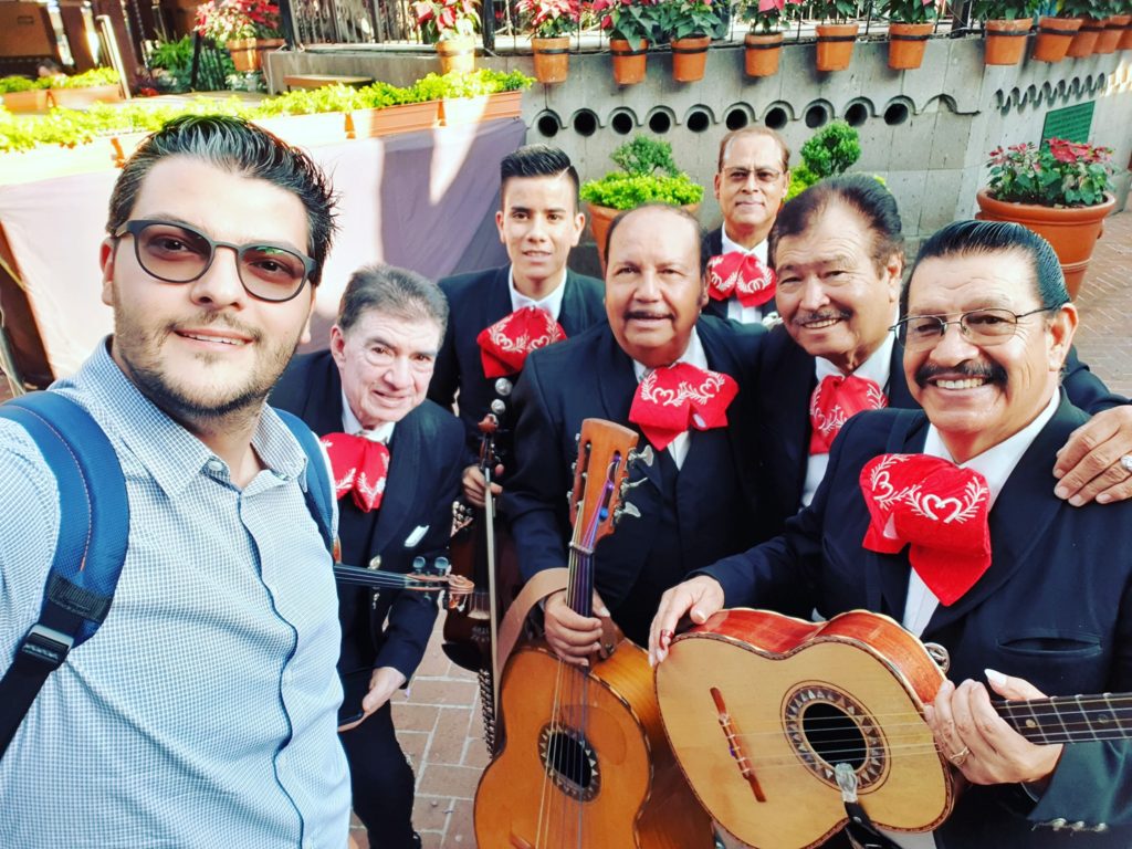 Grup de oameni zâmbind pentru fotografie, alături de muzicieni cu chitare.