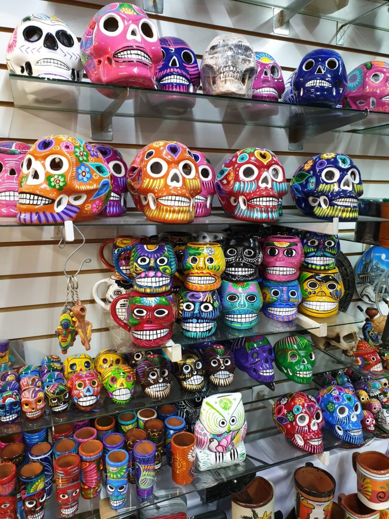 Rafturi cu cranii decorative și obiecte mici viu colorate.