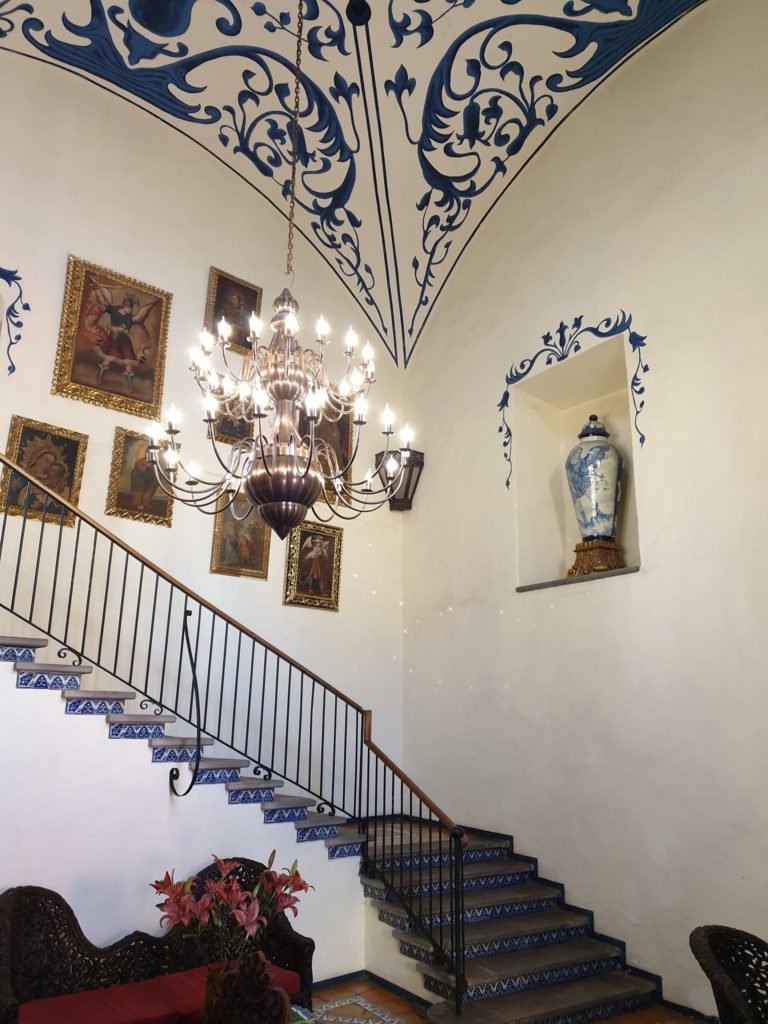 Scară interioară cu balustradă metalică și tavan decorat.