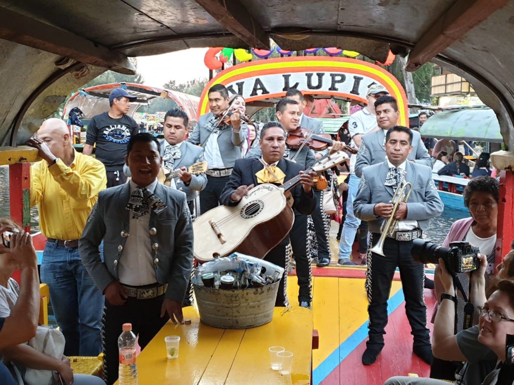 Muzicieni cu instrumente cântând printre pasagerii unei bărci acoperite.