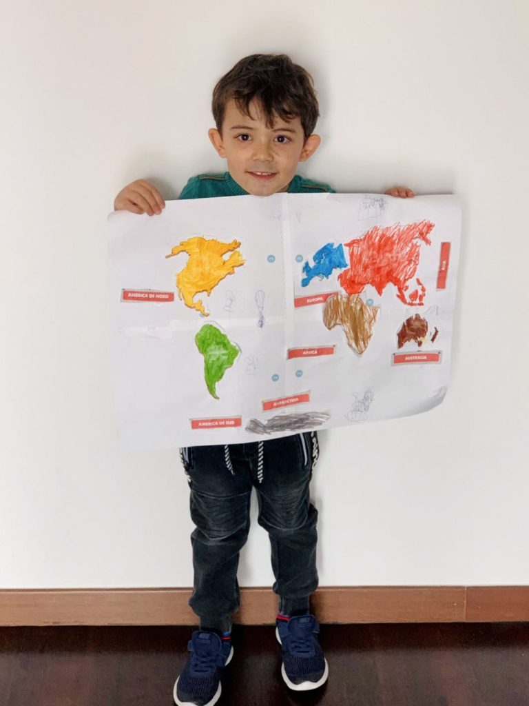 Copil ținând o planșă cu harta lumii