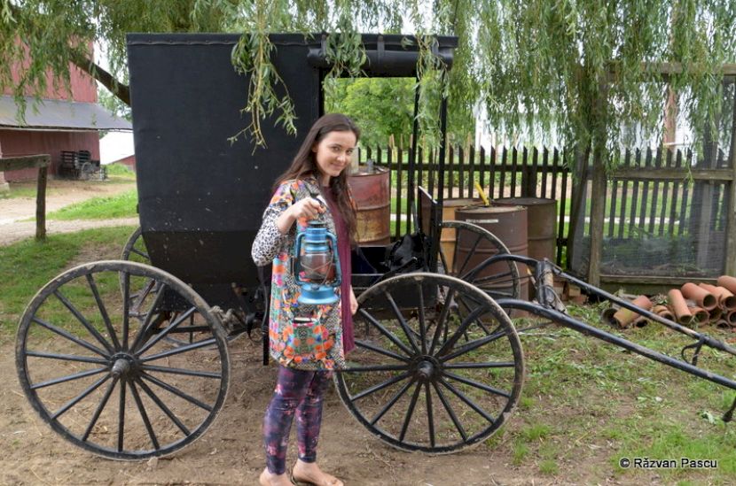 Două persoane lângă o trăsură cu roți mari